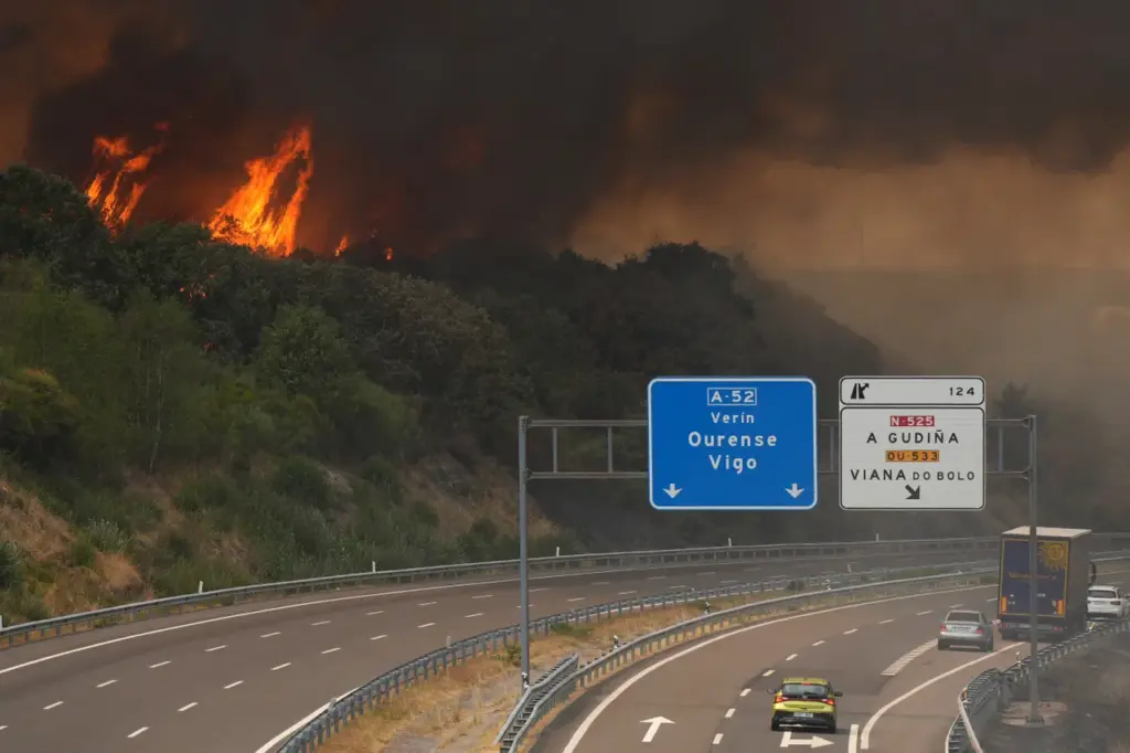 A wildfire burns near a highway in A Gudina, northwestern Spain, on August 15, 2025. All of Spain was on a heatwave alert today, while the weather agency warned that much of the country was at